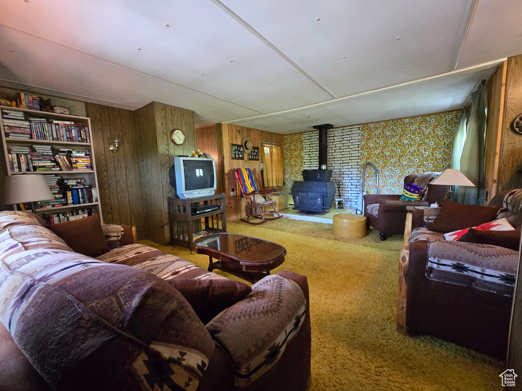 Carpeted living room with a wood stove and wooden walls
