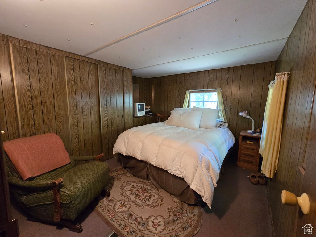 Bedroom featuring wood walls and carpet