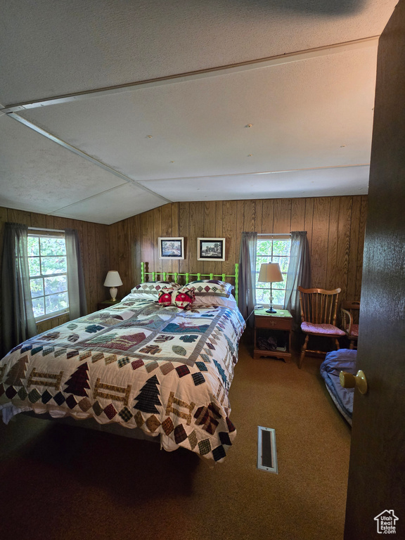 Carpeted bedroom with wood walls and lofted ceiling