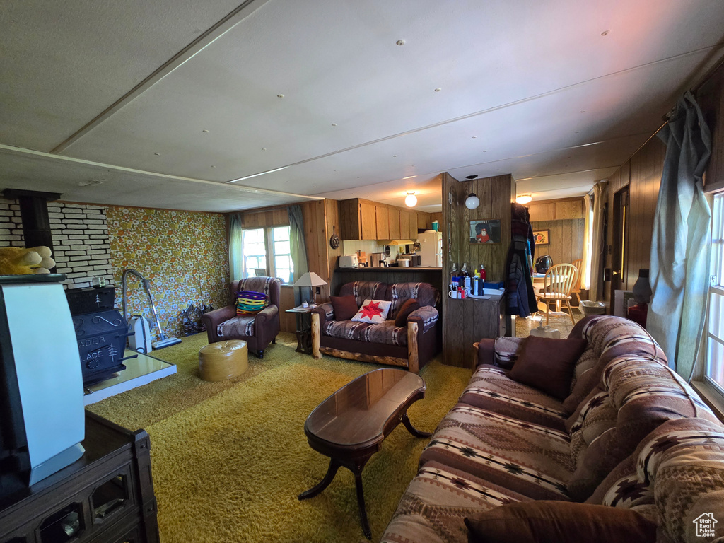 Living area with a wood stove, carpet flooring, and wallpapered walls