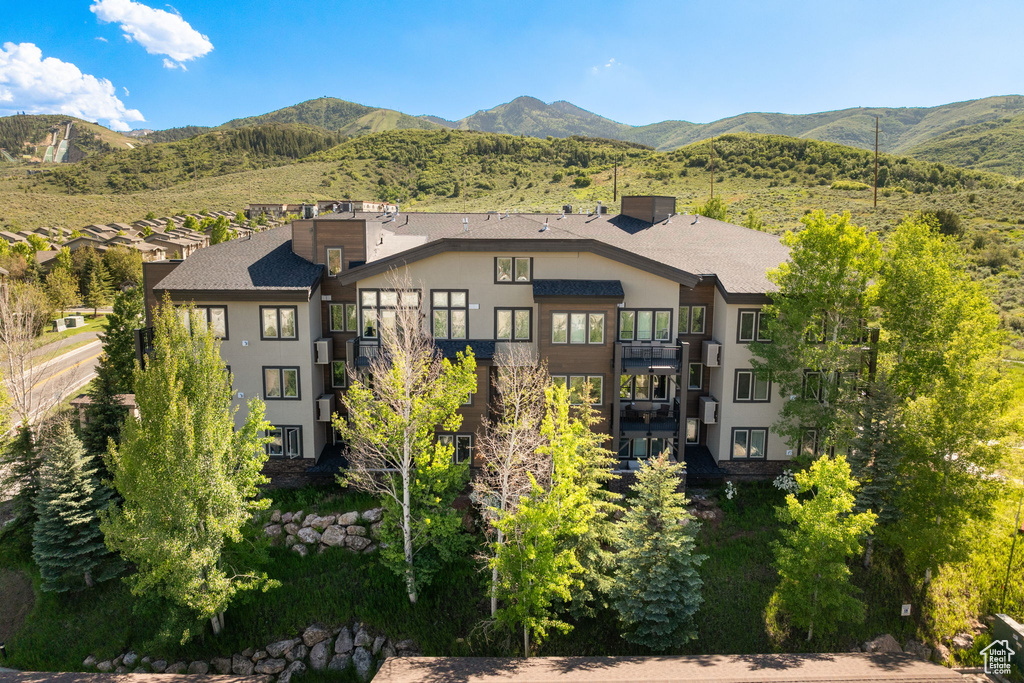 Back of property featuring a balcony, stucco siding, a mountain view, and stairway