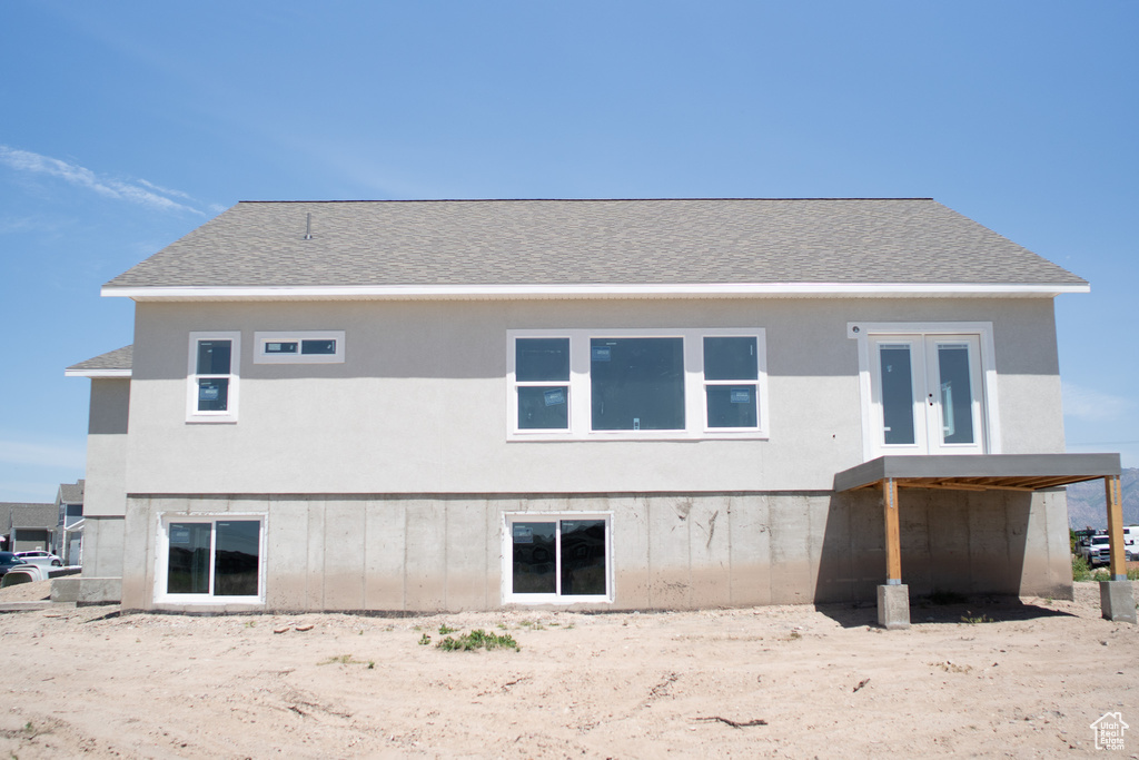 Rear view of house with a shingled roof and stucco siding
