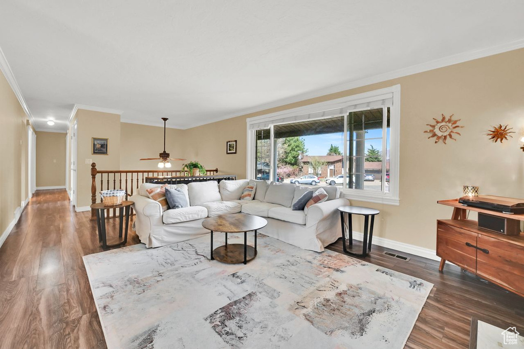 Living room featuring baseboards, a ceiling fan, crown molding, visible vents, and wood finished floors