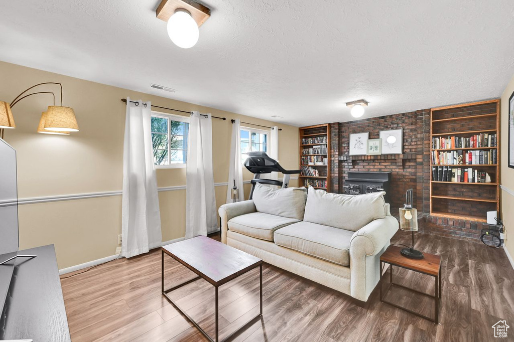 Living room featuring visible vents, built in features, baseboards, a textured ceiling, and wood finished floors