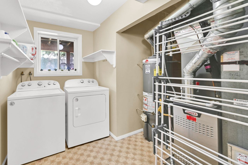 Laundry area with water heater, baseboards, tile patterned floors, washing machine and dryer, and laundry area