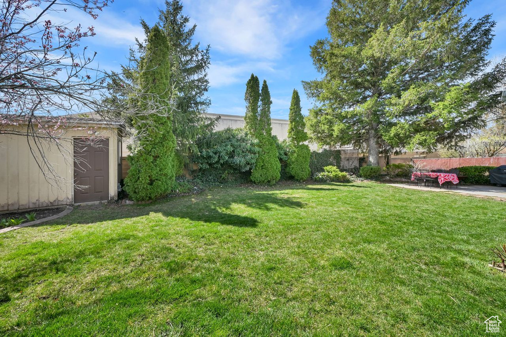 View of yard featuring an outbuilding, a shed, and fence