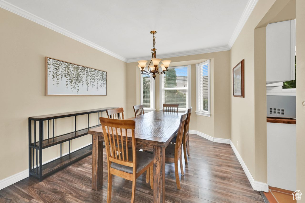 Dining room with a chandelier, dark wood-type flooring, crown molding, and baseboards