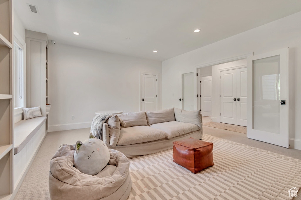 Living area with recessed lighting, light colored carpet, and baseboards