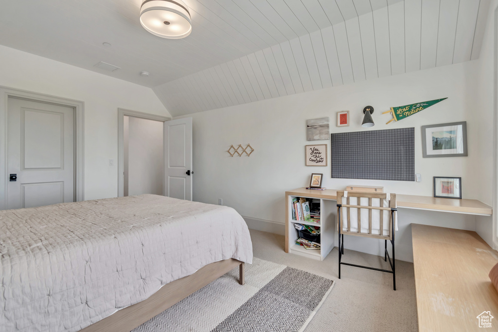 Bedroom featuring vaulted ceiling, carpet floors, and an office area