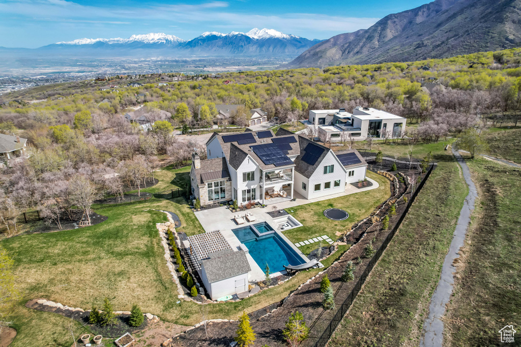 Aerial view of property and surrounding area featuring a pool and a mountainous background