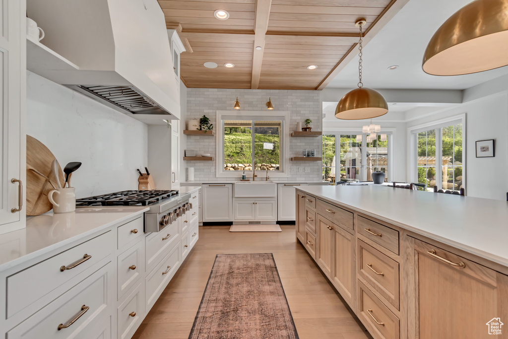 Kitchen featuring open shelves, stainless steel gas cooktop, wall chimney exhaust hood, dishwasher, and backsplash