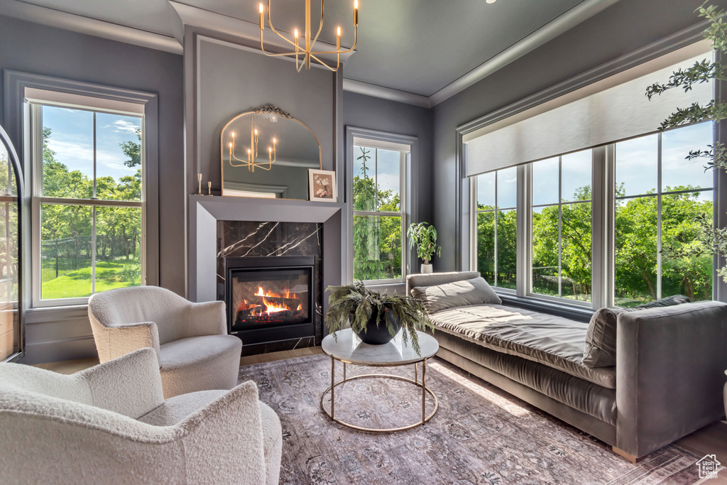 Living area featuring a chandelier, a high end fireplace, and ornamental molding