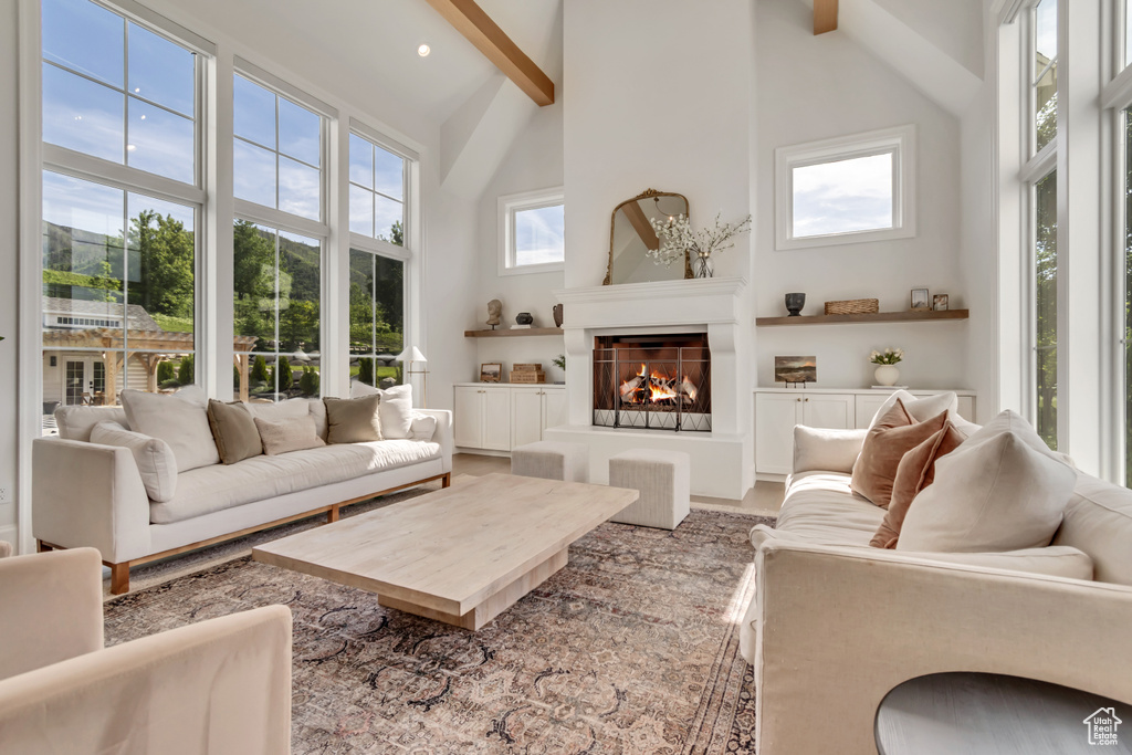 Living room featuring high vaulted ceiling, beamed ceiling, a lit fireplace, and recessed lighting