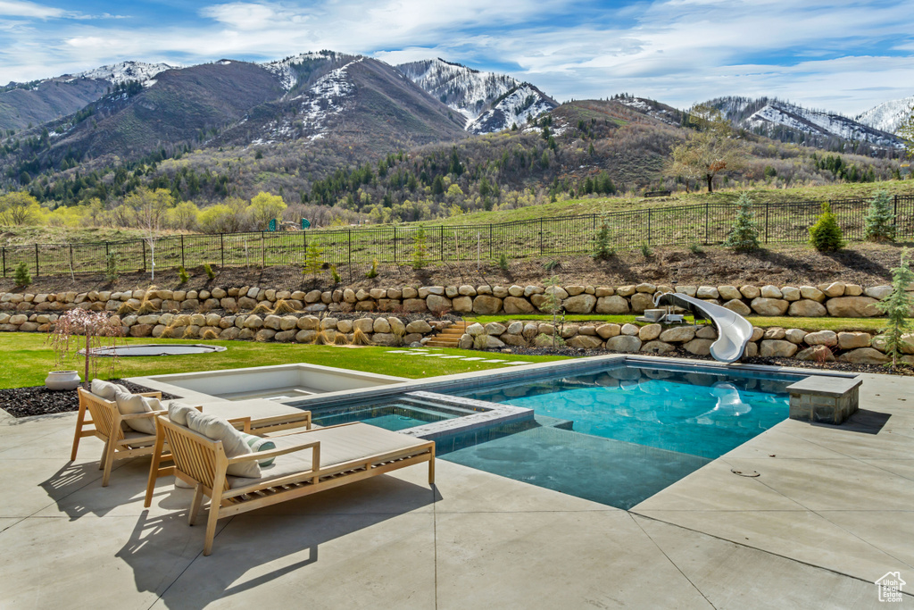 View of swimming pool featuring a patio, a mountain view, a water slide, and a view of rural / pastoral area