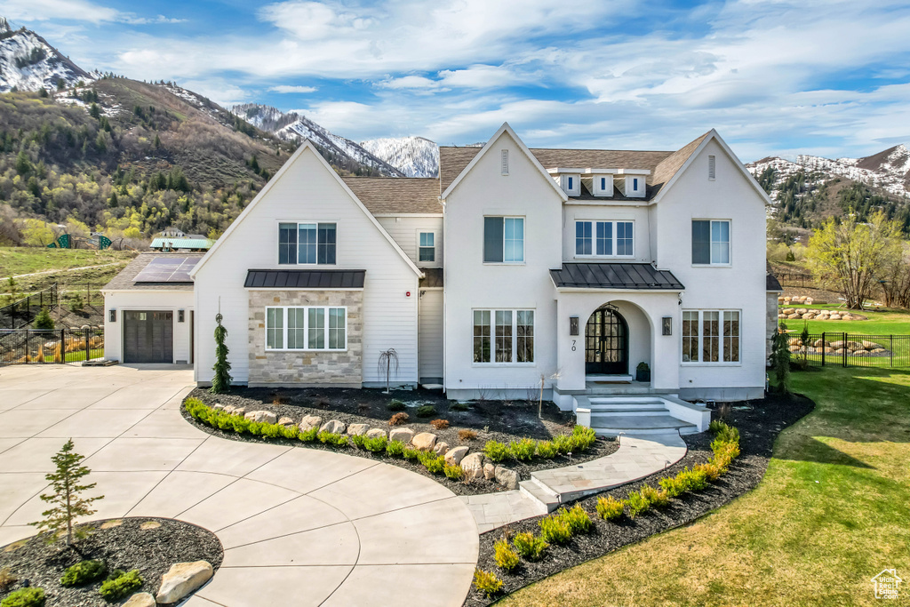 View of front of property with a standing seam roof, a mountain view, concrete driveway, roof mounted solar panels, and metal roof