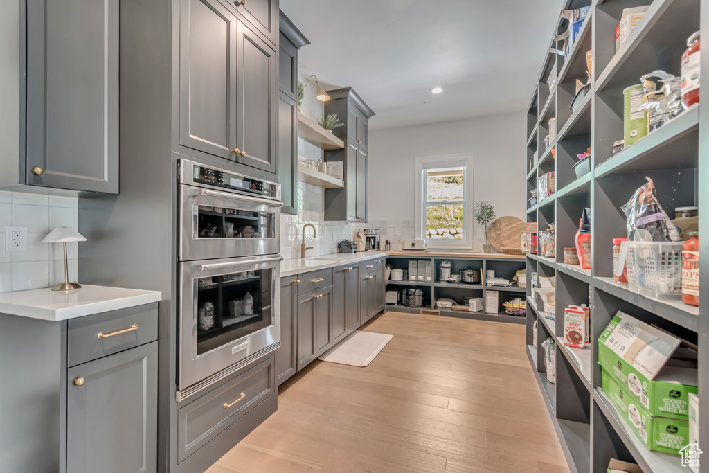 Kitchen with open shelves, gray cabinetry, double oven, and recessed lighting