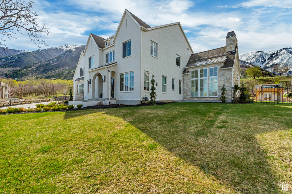 Back of house featuring a mountain view, a chimney, stone siding, and stucco siding