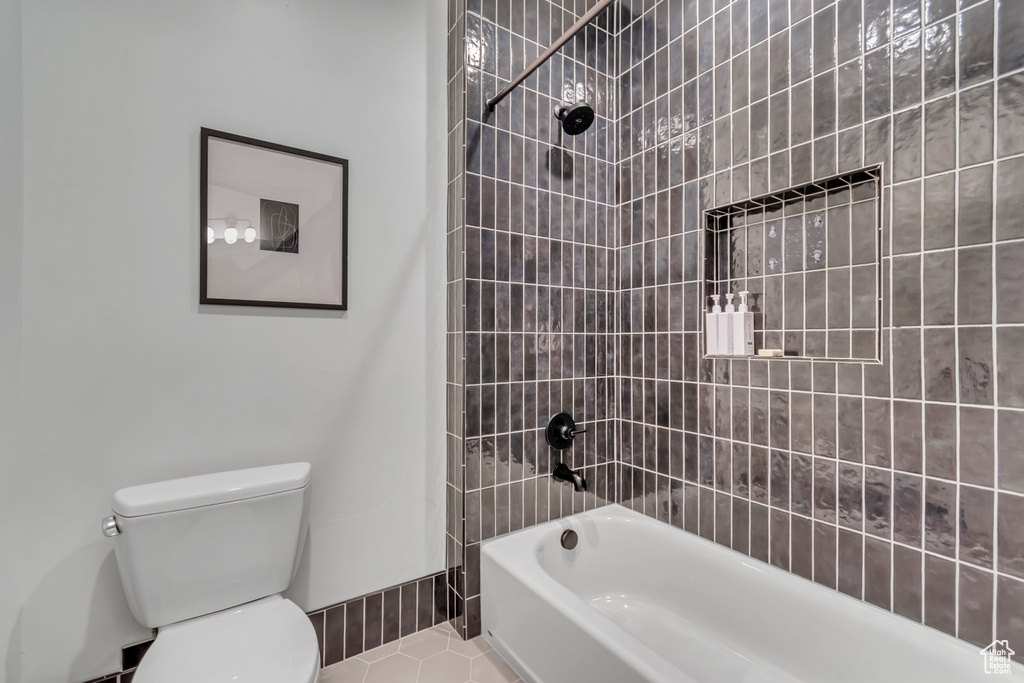 Full bathroom featuring toilet, tile patterned flooring,  shower combination, and baseboards
