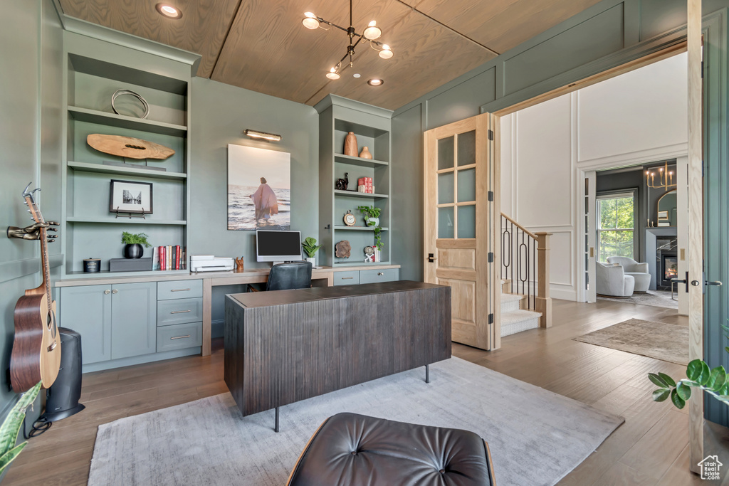 Home office featuring built in shelves, wood finished floors, wooden ceiling, recessed lighting, and a chandelier