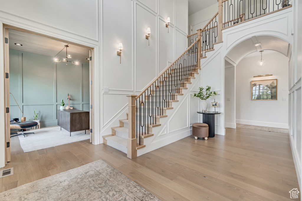 Stairs featuring a decorative wall, wood finished floors, a high ceiling, and arched walkways
