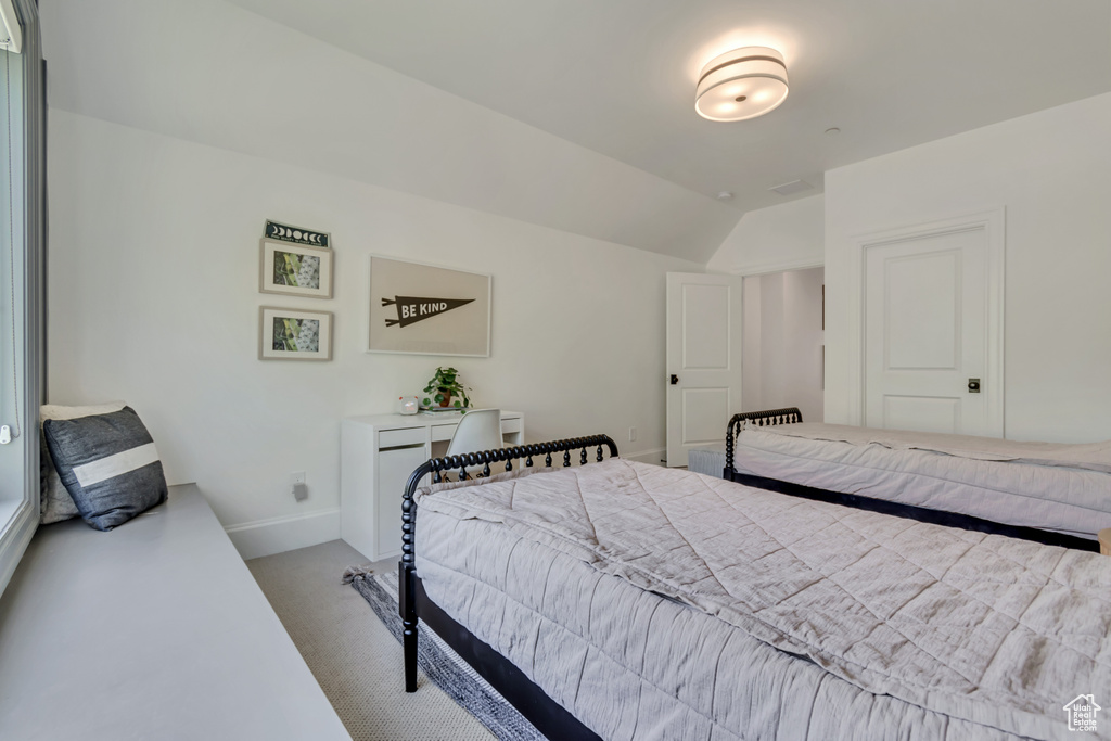 Carpeted bedroom with vaulted ceiling and baseboards
