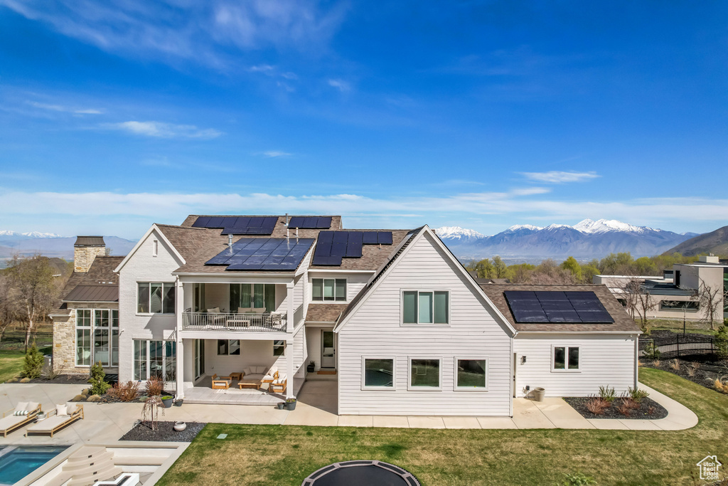 Back of property featuring a patio, a balcony, and solar panels