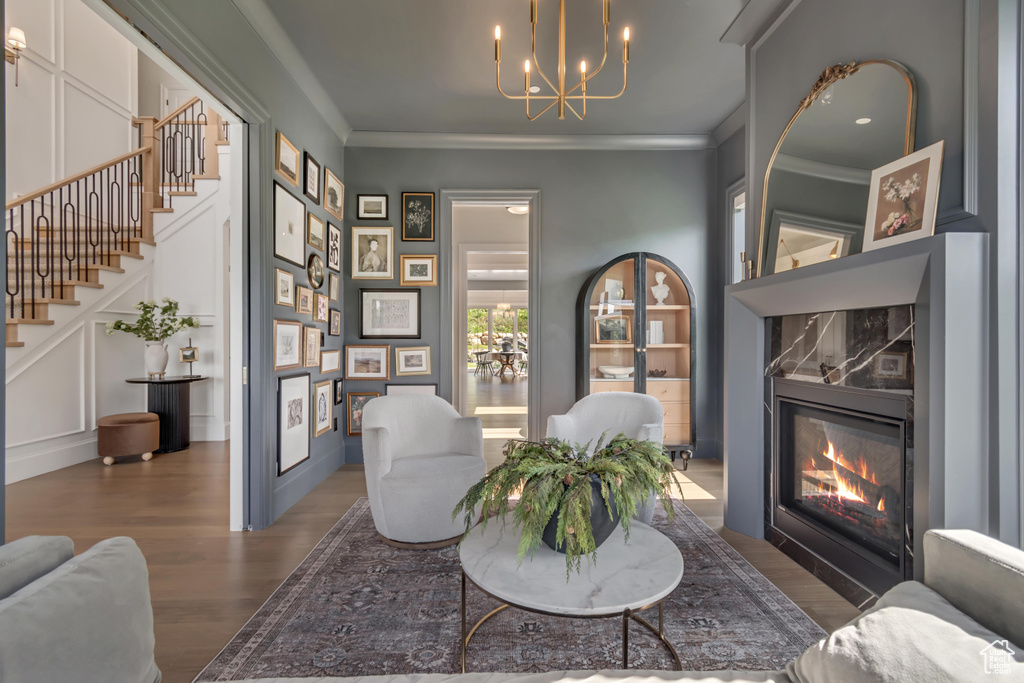 Sitting room featuring wood finished floors, a chandelier, stairs, a fireplace, and ornamental molding