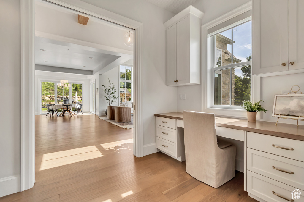 Office space with built in desk, light wood-style floors, and baseboards