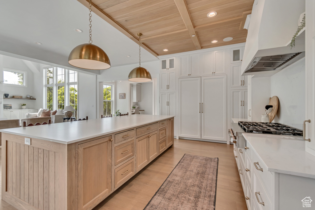 Kitchen featuring custom exhaust hood, wooden ceiling with exposed beams, light countertops, a center island, and light wood-type flooring