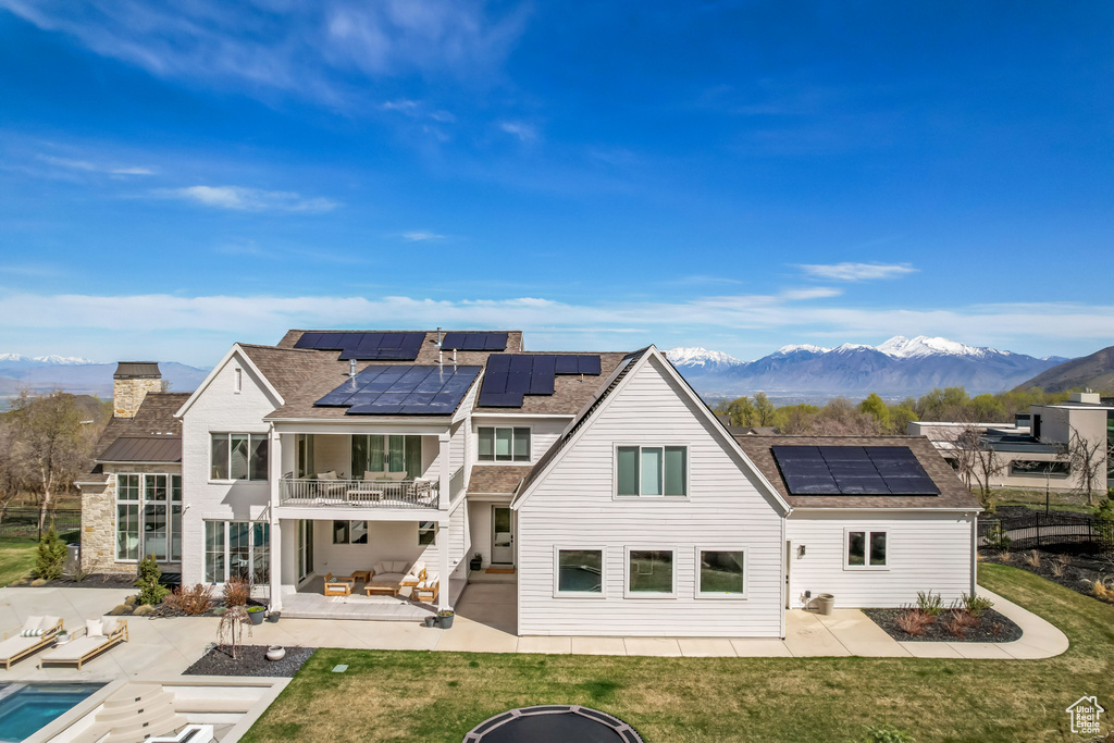Back of property with a balcony, a patio, and solar panels