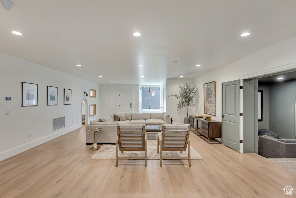 Living room with light wood finished floors, recessed lighting, baseboards, and arched walkways