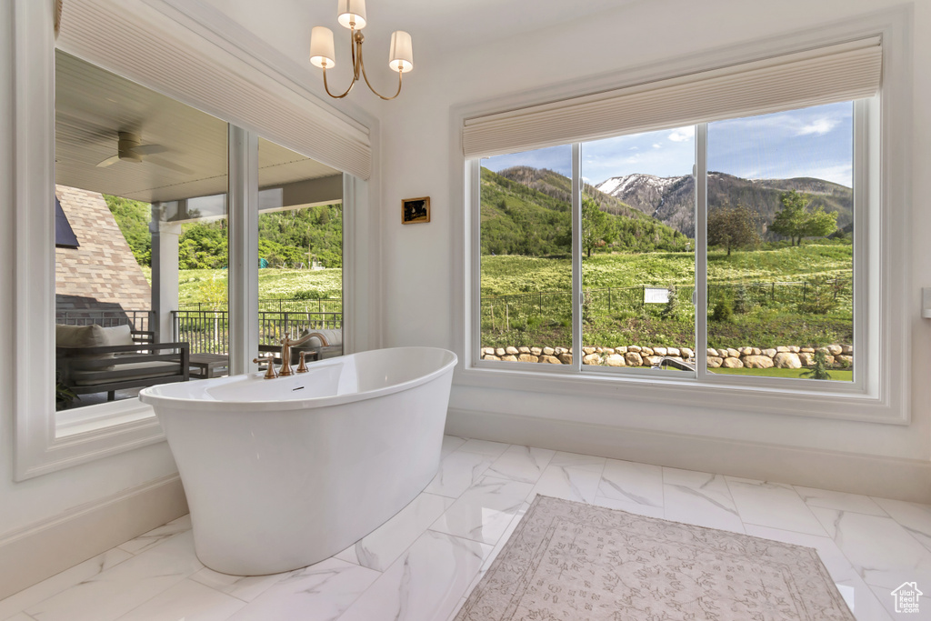 Full bathroom with a mountain view, marble finish floors, a soaking tub, and baseboards