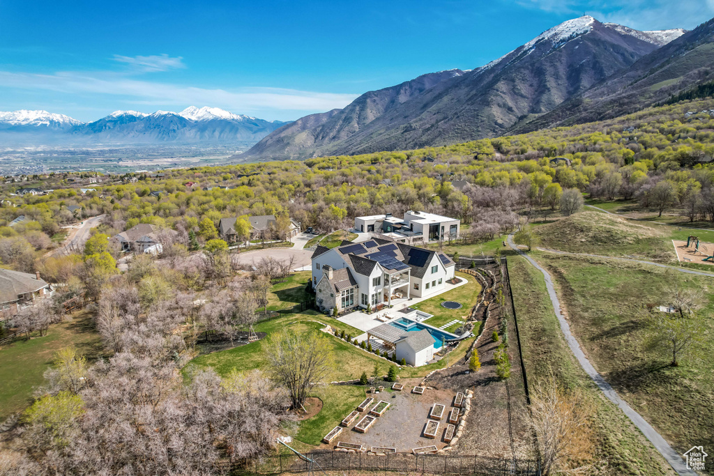 Aerial view of property and surrounding area with mountains, a pool, and a forest