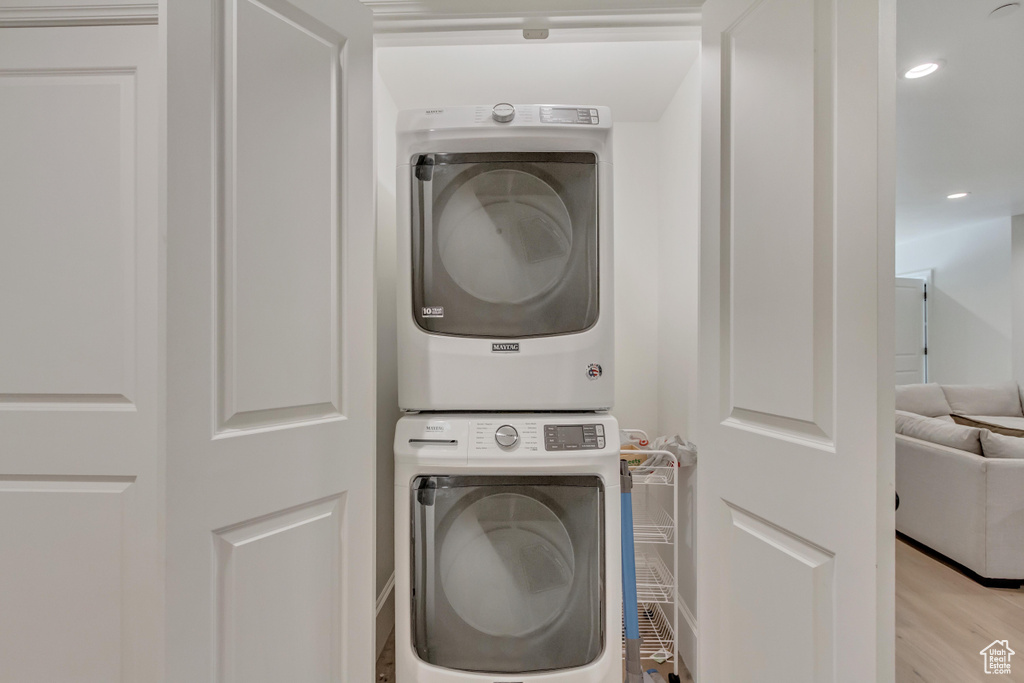 Laundry room featuring stacked washer / dryer, light wood-style floors, and recessed lighting