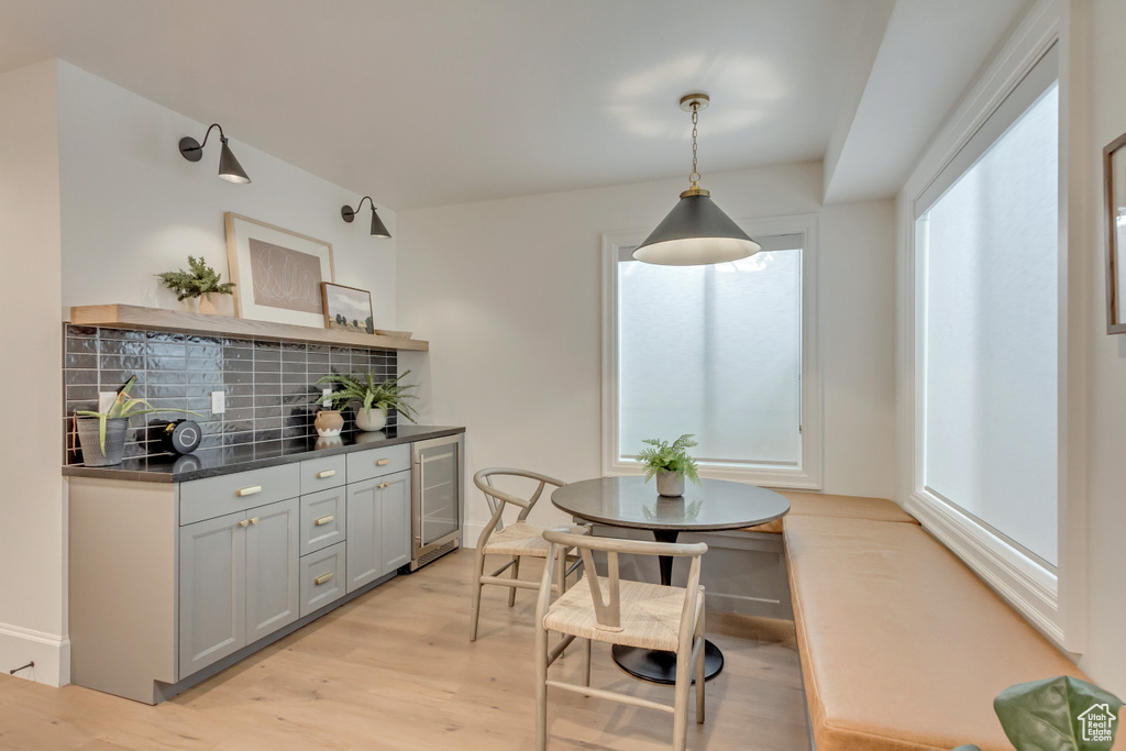 Dining room featuring beverage cooler, a dry bar, and light wood finished floors