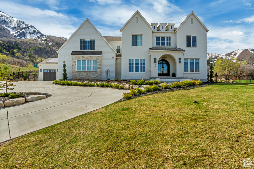 View of front of property with a standing seam roof, driveway, metal roof, a mountain view, and stucco siding