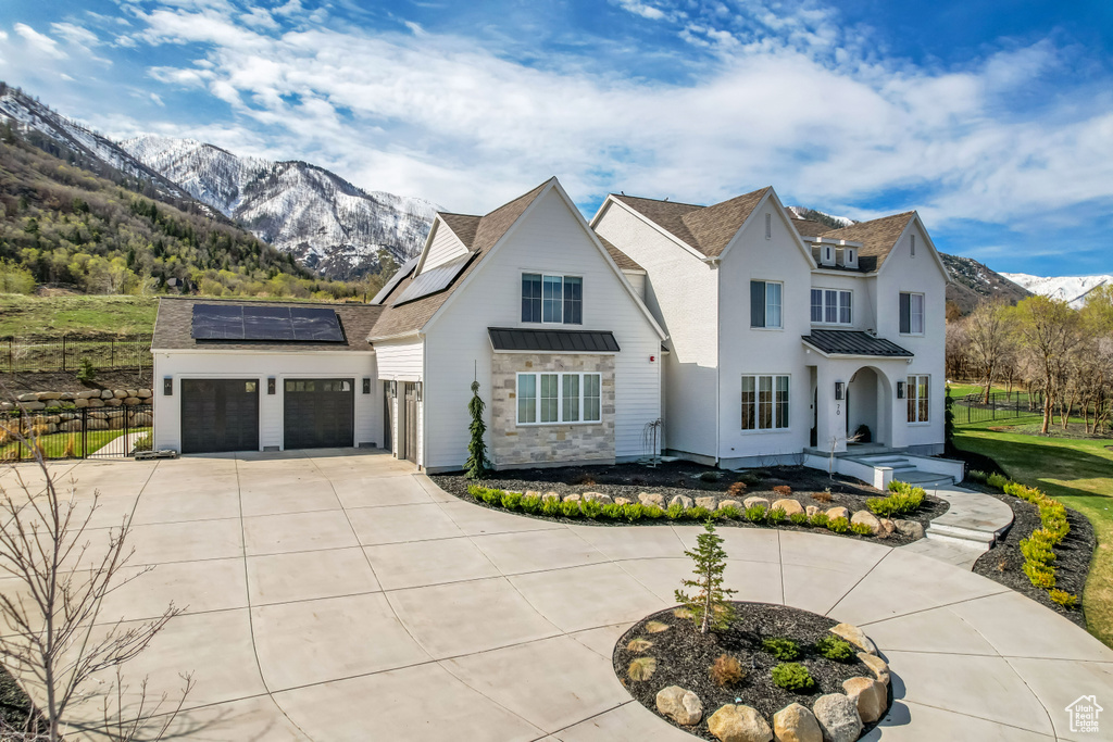 View of front of house featuring a standing seam roof, driveway, a mountain view, solar panels, and metal roof