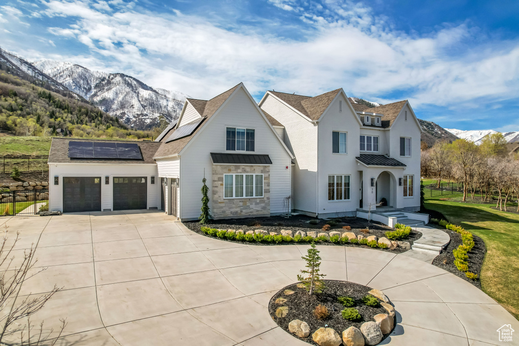 View of front of home with a standing seam roof, curved driveway, solar panels, a mountain view, and metal roof