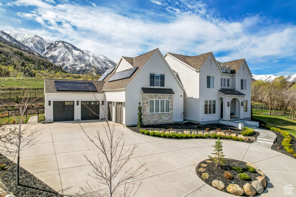 View of front of house with a standing seam roof, concrete driveway, roof mounted solar panels, metal roof, and a mountain view