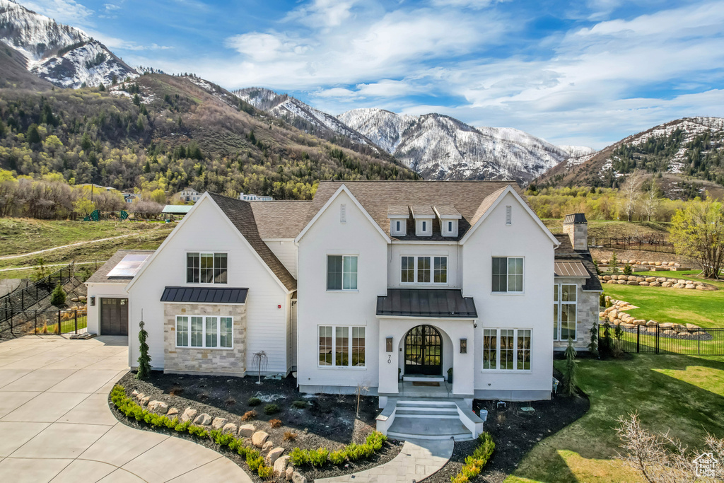 View of front facade with a standing seam roof, a chimney, concrete driveway, and a mountain view