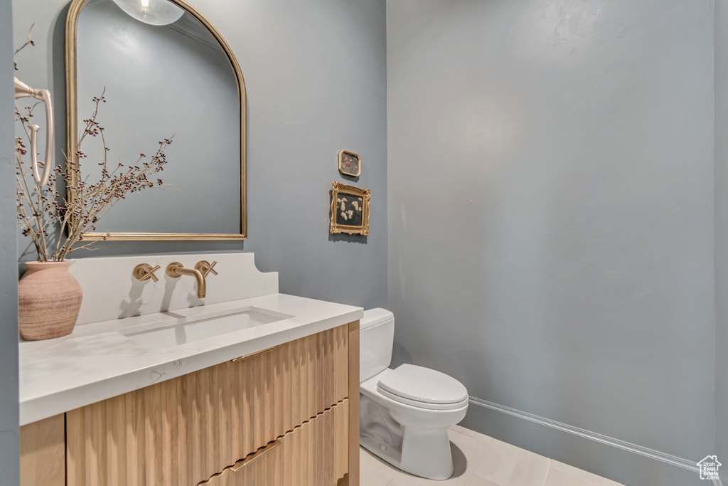 Half bath with toilet, vanity, and tile patterned floors