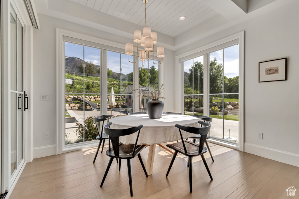 Dining space with a chandelier, healthy amount of natural light, light wood-style flooring, and baseboards