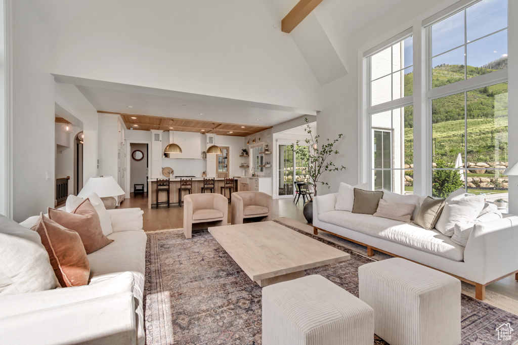 Living area with beamed ceiling, a towering ceiling, light wood-style flooring, and recessed lighting