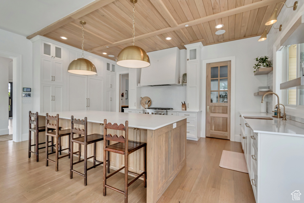 Kitchen with wood ceiling with exposed beams, light wood-style flooring, ventilation hood, open shelves, and a sink