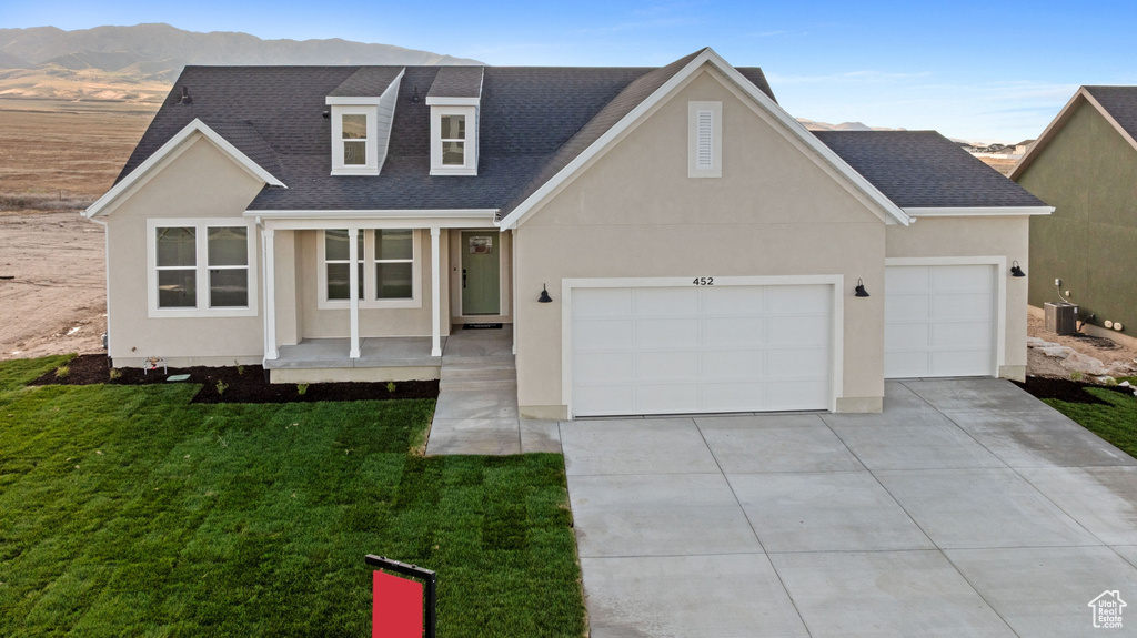 Traditional-style home with driveway, a shingled roof, an attached garage, stucco siding, and a front lawn