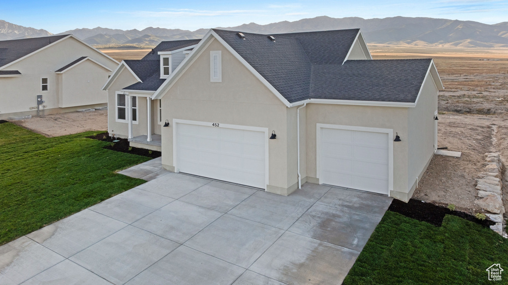 View of front of property featuring a mountain view, roof with shingles, concrete driveway, and a garage