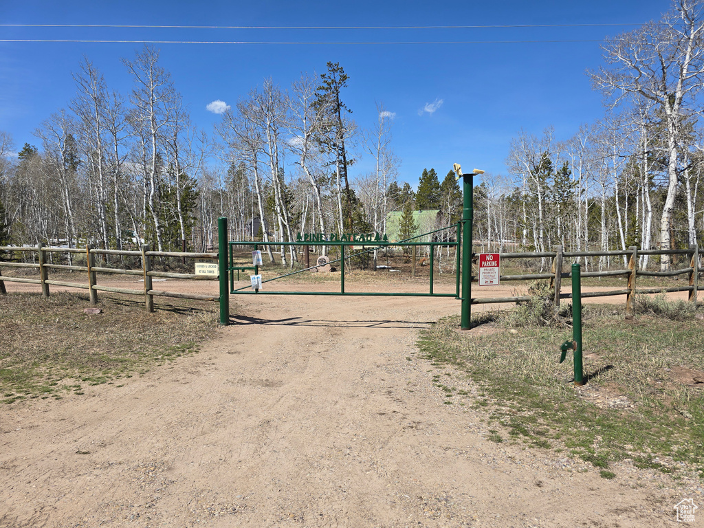 View of community with fence and dirt driveway