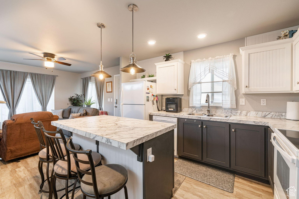 Kitchen featuring a sink, light countertops, a breakfast bar, and white appliances
