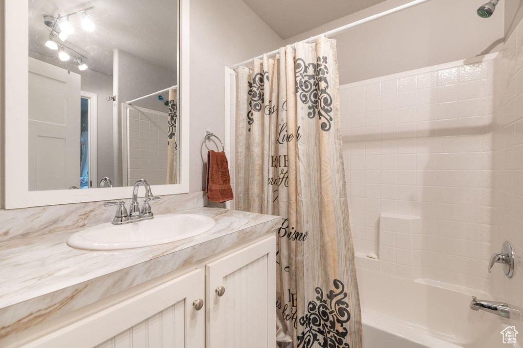 Bathroom with shower / bath combination with curtain and vanity
