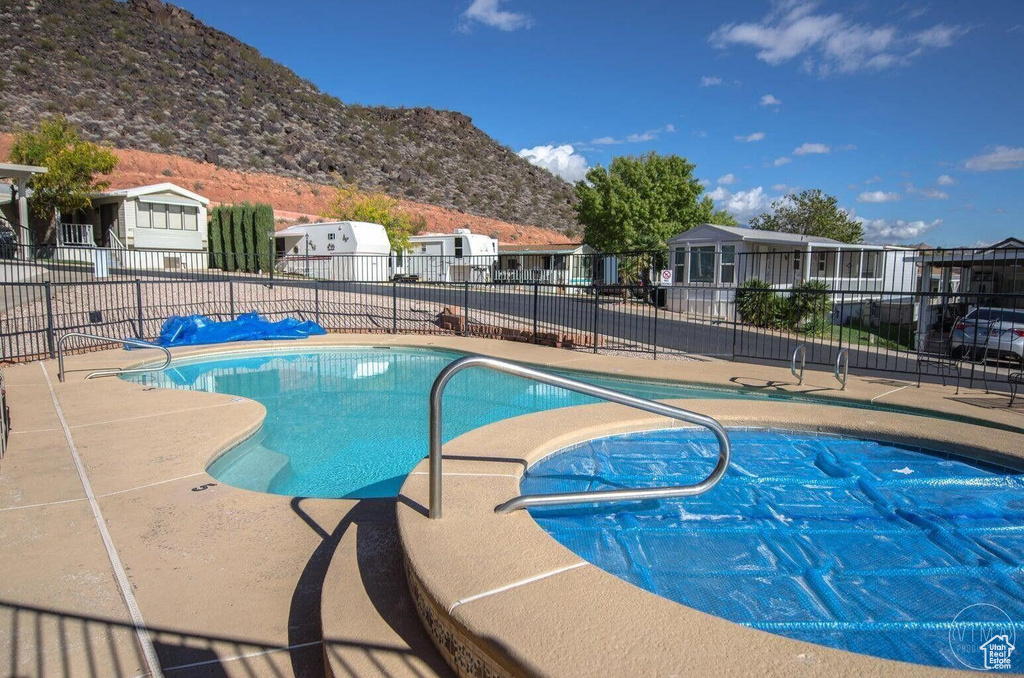 Community pool with a patio area, a mountain view, fence, and a residential view